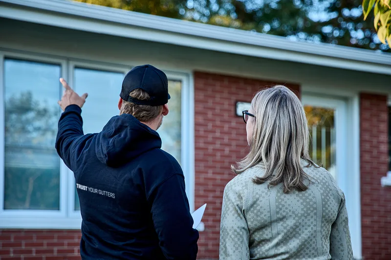 Installer adjusting a downspout elbow during a gutter cleaning